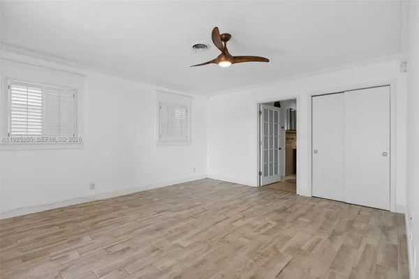 a view of empty room with wooden floor and ceiling fan