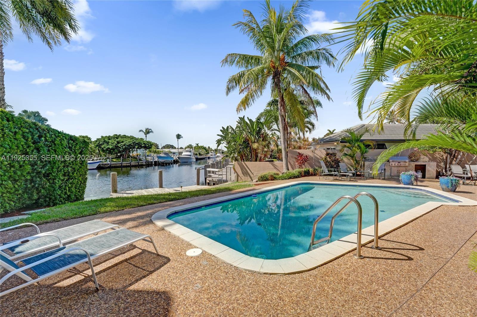 4060 Northeast 26th Avenue Lighthouse Point, FL 33064 - Photo 27 of 34 a view of a swimming pool with a yard and palm trees