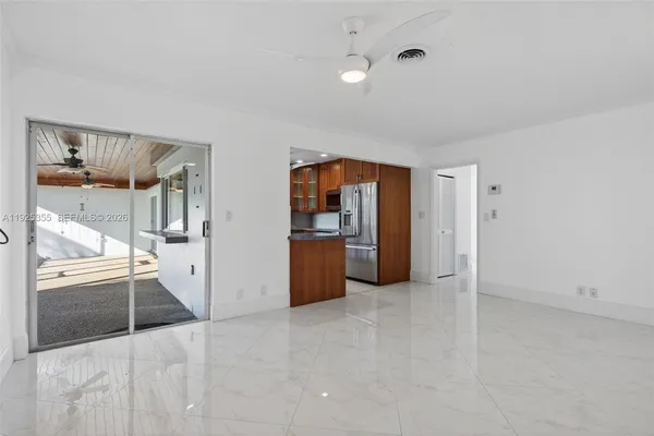 an empty room with wooden floor ceiling fan and windows