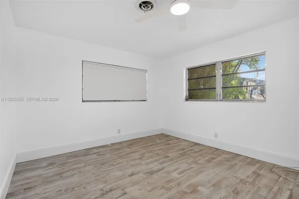 a view of empty room with wooden floor and fan