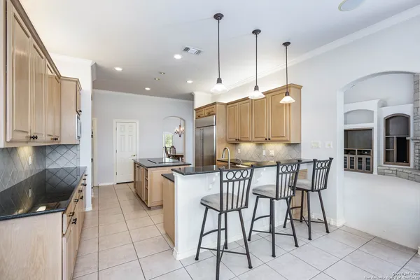 a kitchen with stainless steel appliances kitchen island granite countertop a table chairs and a refrigerator