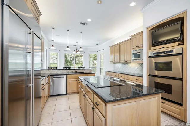 a kitchen with stainless steel appliances granite countertop a sink a stove and a refrigerator