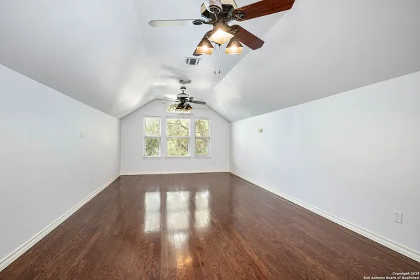 an empty room with wooden floor chandelier and windows