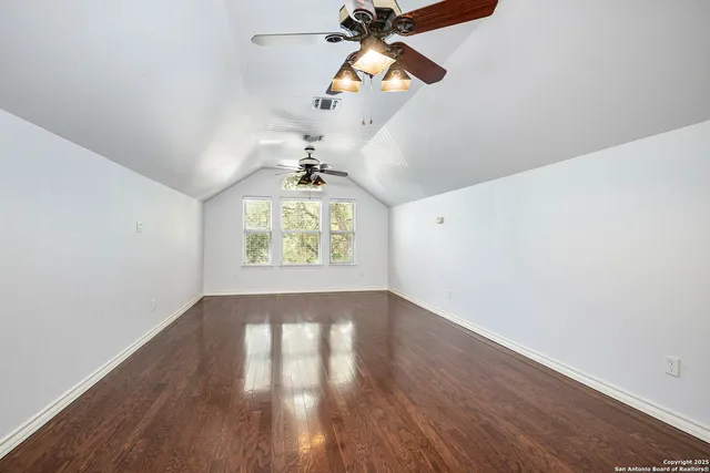 an empty room with wooden floor chandelier and windows