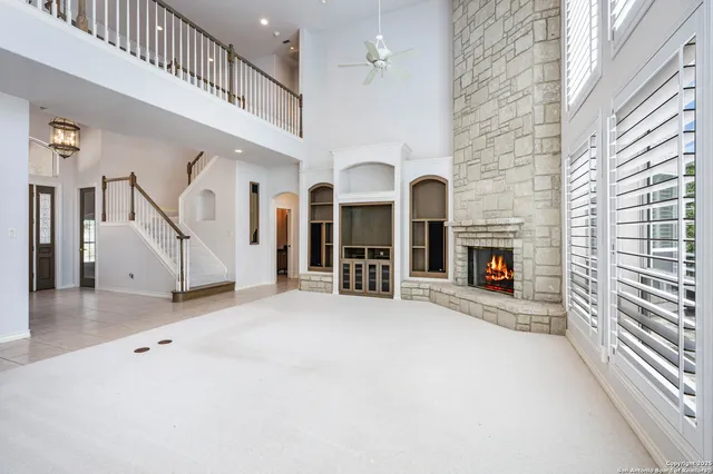 a view of an empty room with fireplace and windows