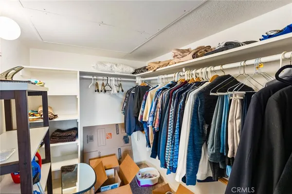a view of walk in closet with clothes and shoes