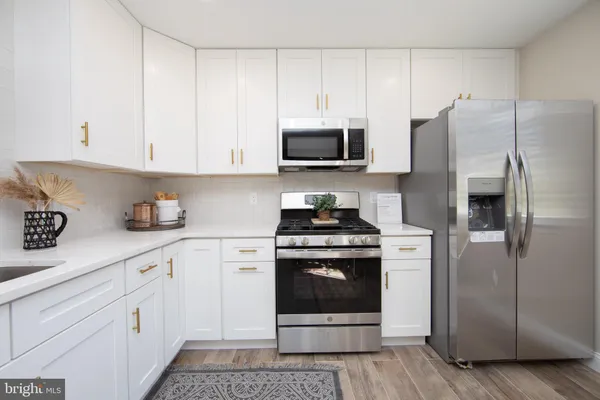 a kitchen with stainless steel appliances granite countertop a refrigerator stove and white cabinets