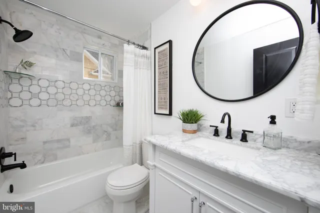 a bathroom with a granite countertop sink a toilet and a mirror