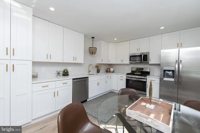 a kitchen with stainless steel appliances granite countertop a refrigerator a stove a sink a dining table and chairs