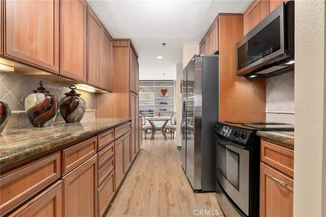 a kitchen with stainless steel appliances granite countertop a sink dishwasher stove and cabinets with wooden floor