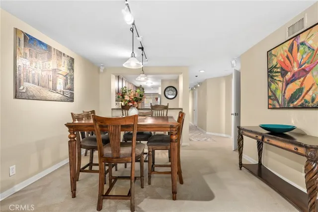 a view of a dining room and livingroom with furniture wooden floor a rug a flat screen tv a painting and a chandelier