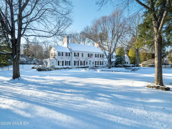 a view of a house with a yard and large trees