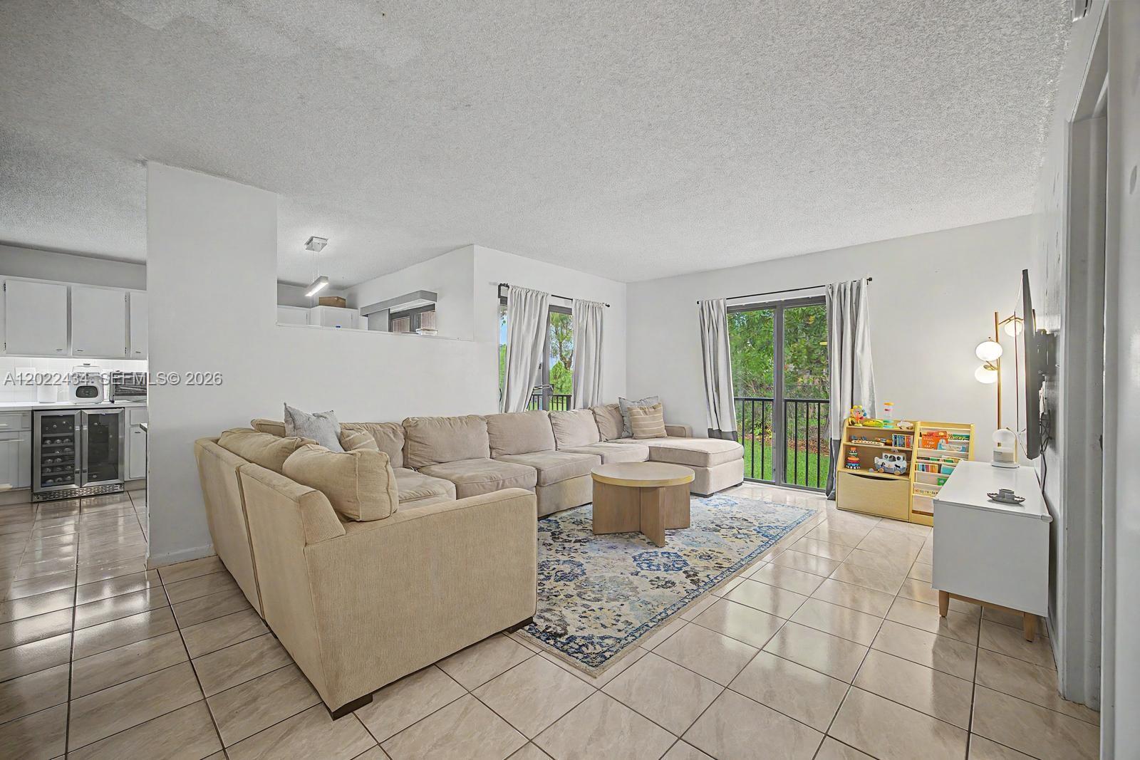 13045 Southwest 68th Street, Unit 111 Miami, FL 33183 - Photo 3 of 15 a living room with furniture a large window and a dining table