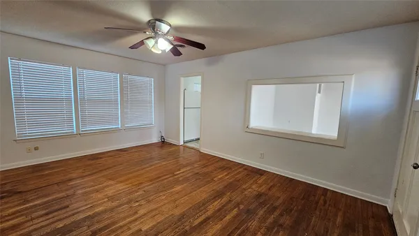 a view of an empty room with window and wooden floor