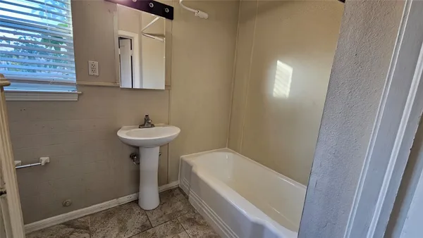 a bathroom with a sink a bath tub and a window