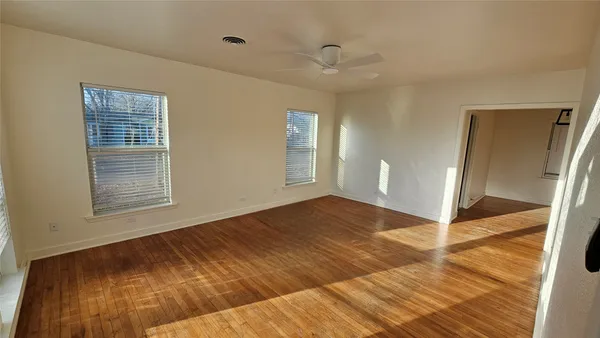 a view of an empty room with wooden floor and a window
