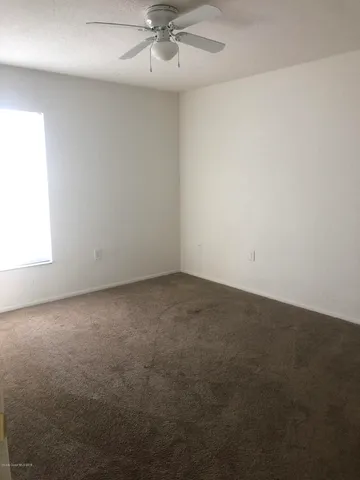 an empty room with a fan & a window