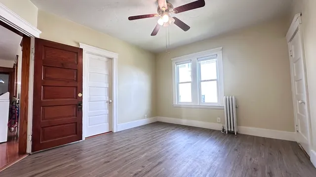 an empty room with wooden floor closet and windows