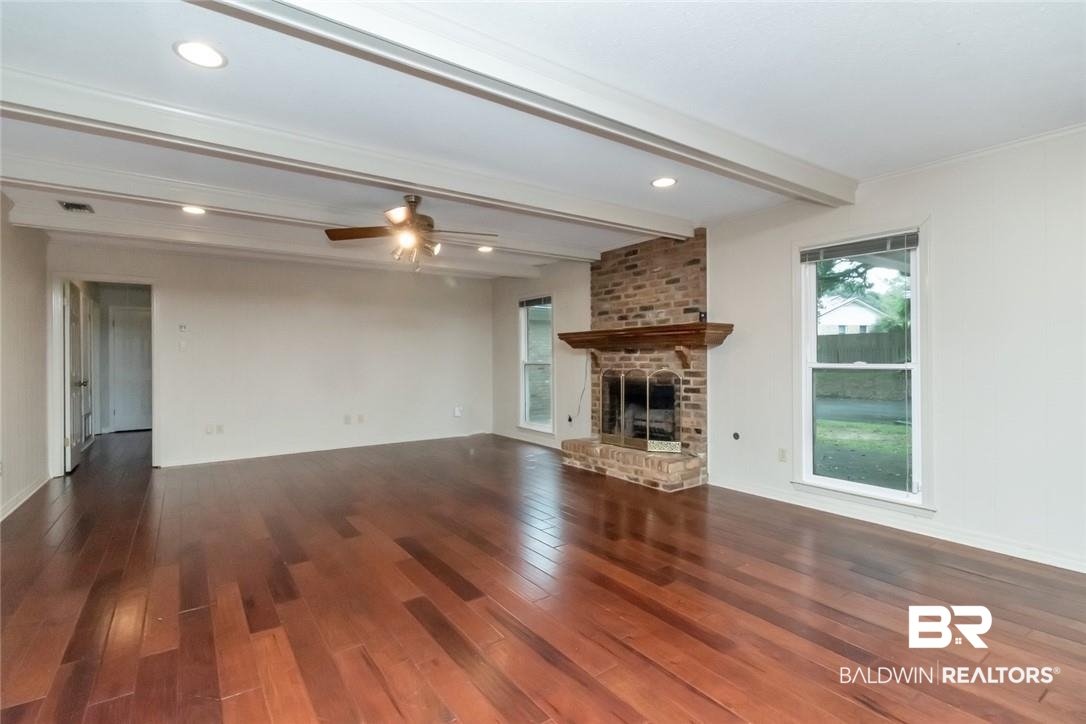 6109 Timberly Road North Mobile, AL 36609 - Photo 13 of 26 Unfurnished living room with a fireplace, dark hardwood / wood-style flooring, beam ceiling, ceiling fan, and ornamental molding