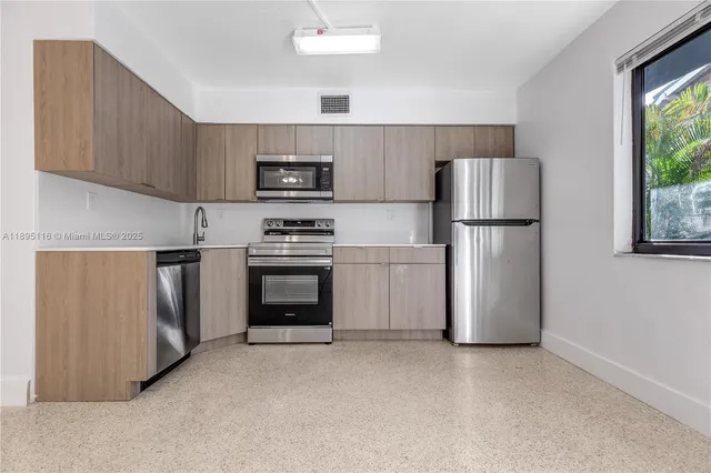 a kitchen with a refrigerator a stove top oven a sink and a window