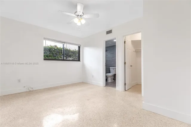 an empty room with windows and fan