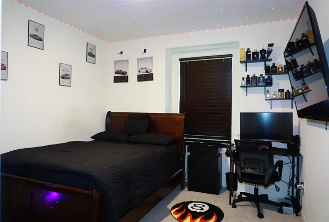 a bed sitting in a bedroom next to a window with chair and wooden floor