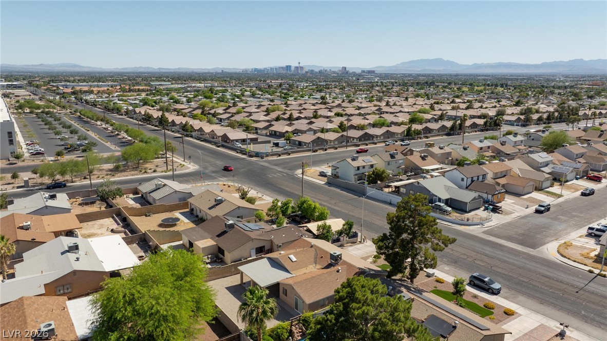 3640 North Walnut Road Las Vegas, NV 89115 - Photo 37 of 38 An aerial perspective reveals a vast residential community under the clear sky, with distant cityscapes and mountains framing the horizon.