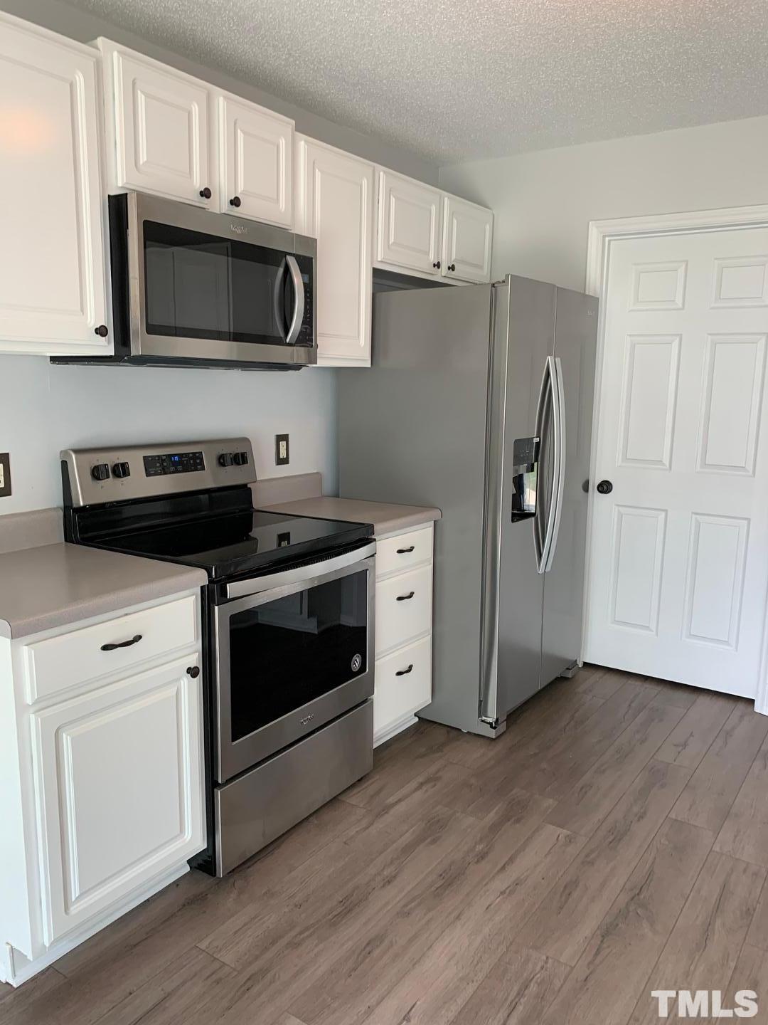 6120 Saybrooke Drive Raleigh, NC 27604 - Photo 4 of 7 a kitchen with stainless steel appliances a white stove a microwave and a hard wood floors