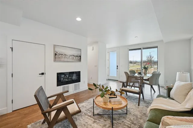 a living room with furniture and a dining table with wooden floor