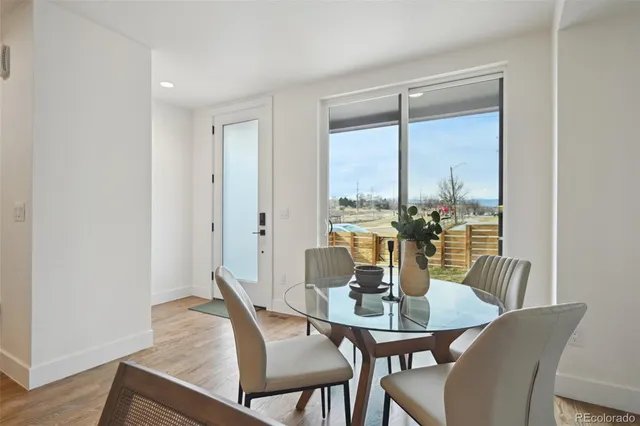 a kitchen with kitchen island granite countertop a dining table chairs wooden cabinets and white appliances