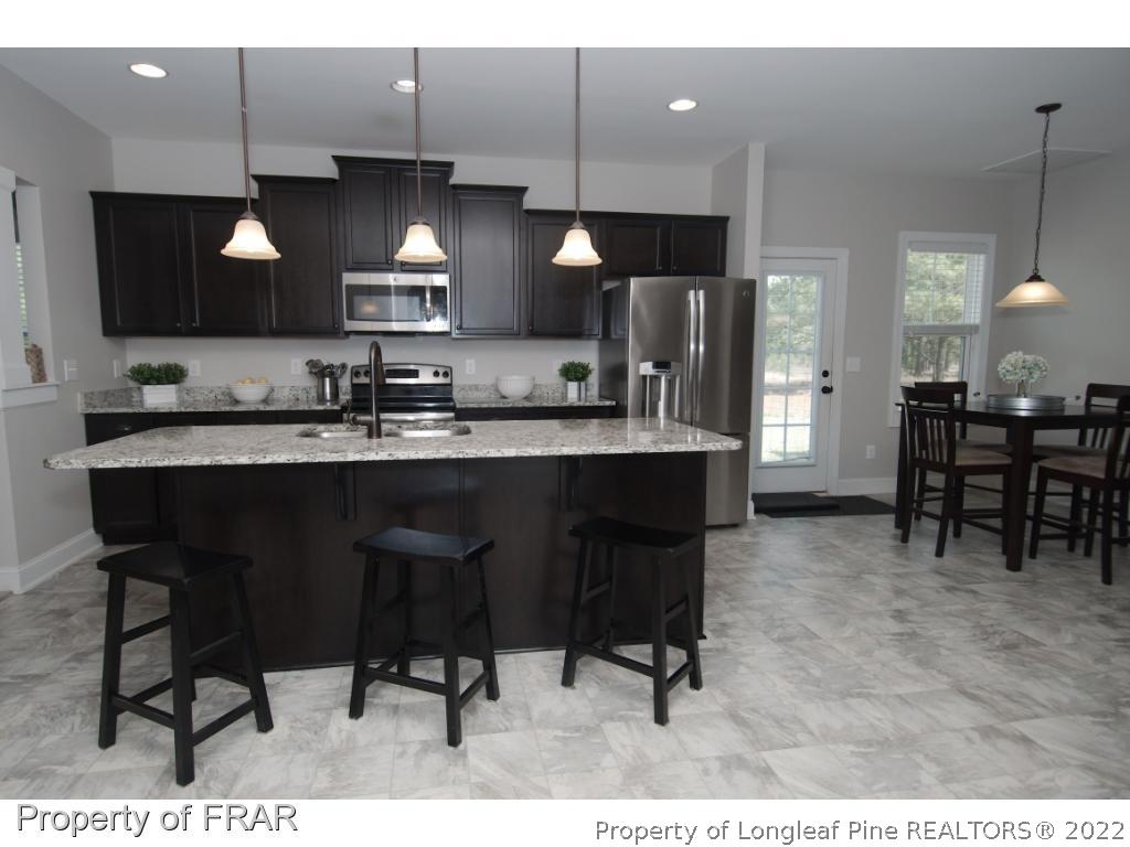 105 Caulfield Road Aberdeen, NC 28315 - Photo 6 of 36 a kitchen with stainless steel appliances kitchen island granite countertop a table chairs sink and cabinets