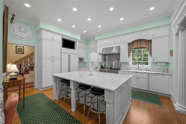 a kitchen with stainless steel appliances granite countertop a stove a sink dishwasher and a refrigerator with wooden floor