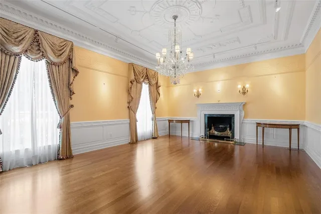 a view of an empty room with wooden floor fireplace and a window