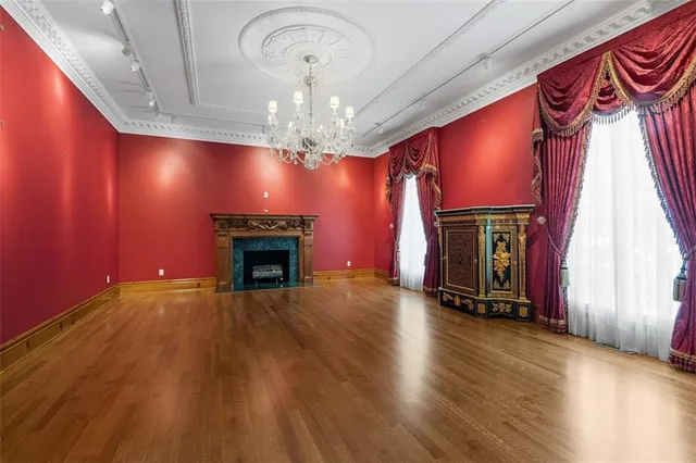 a view of an empty room with wooden floor fireplace and a window