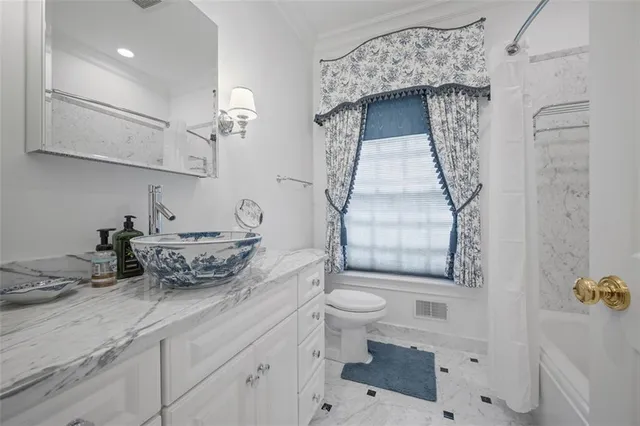 a bathroom with a granite countertop bathtub sink vanity mirror and toilet