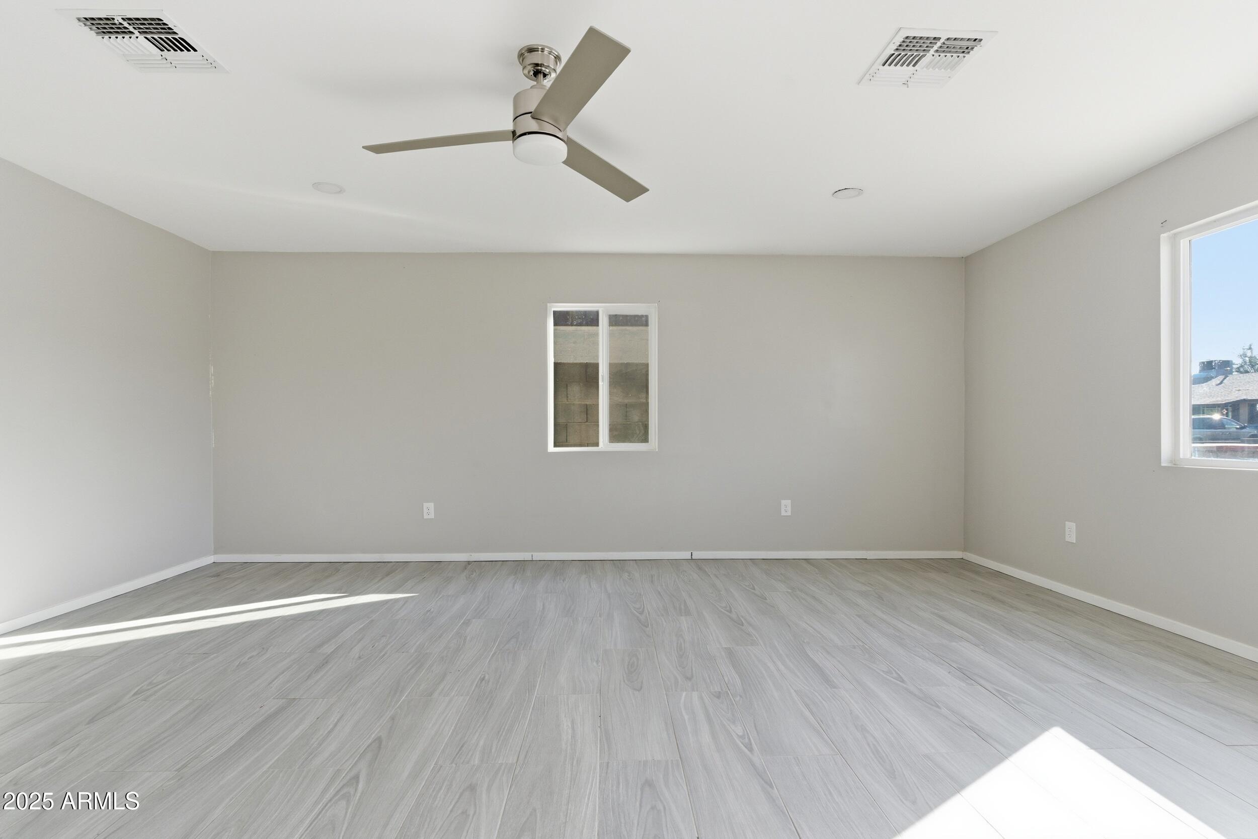 7150 West Montecito Avenue Phoenix, AZ 85033 - Photo 11 of 30 an empty room with wooden floor fan and windows