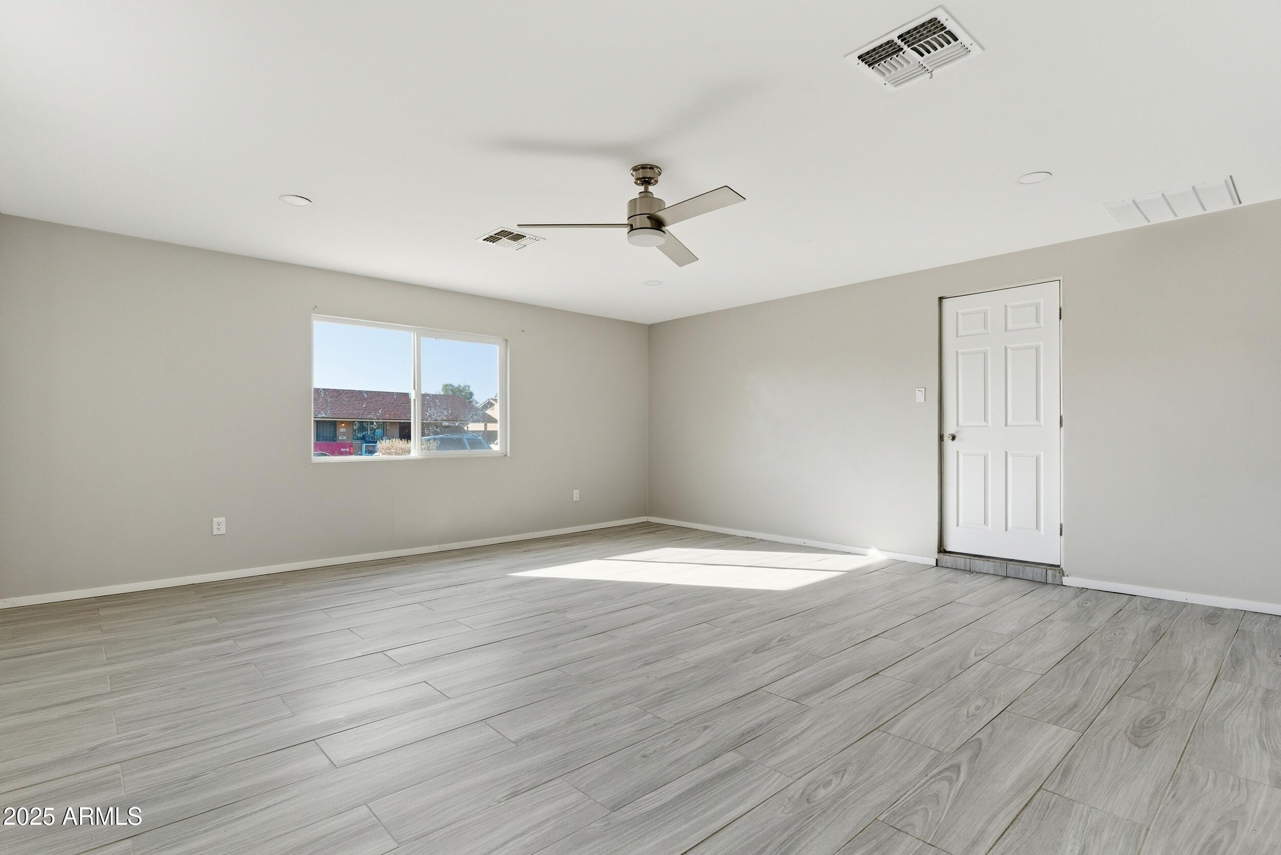 7150 West Montecito Avenue Phoenix, AZ 85033 - Photo 12 of 30 an empty room with wooden floor ceiling fan and windows