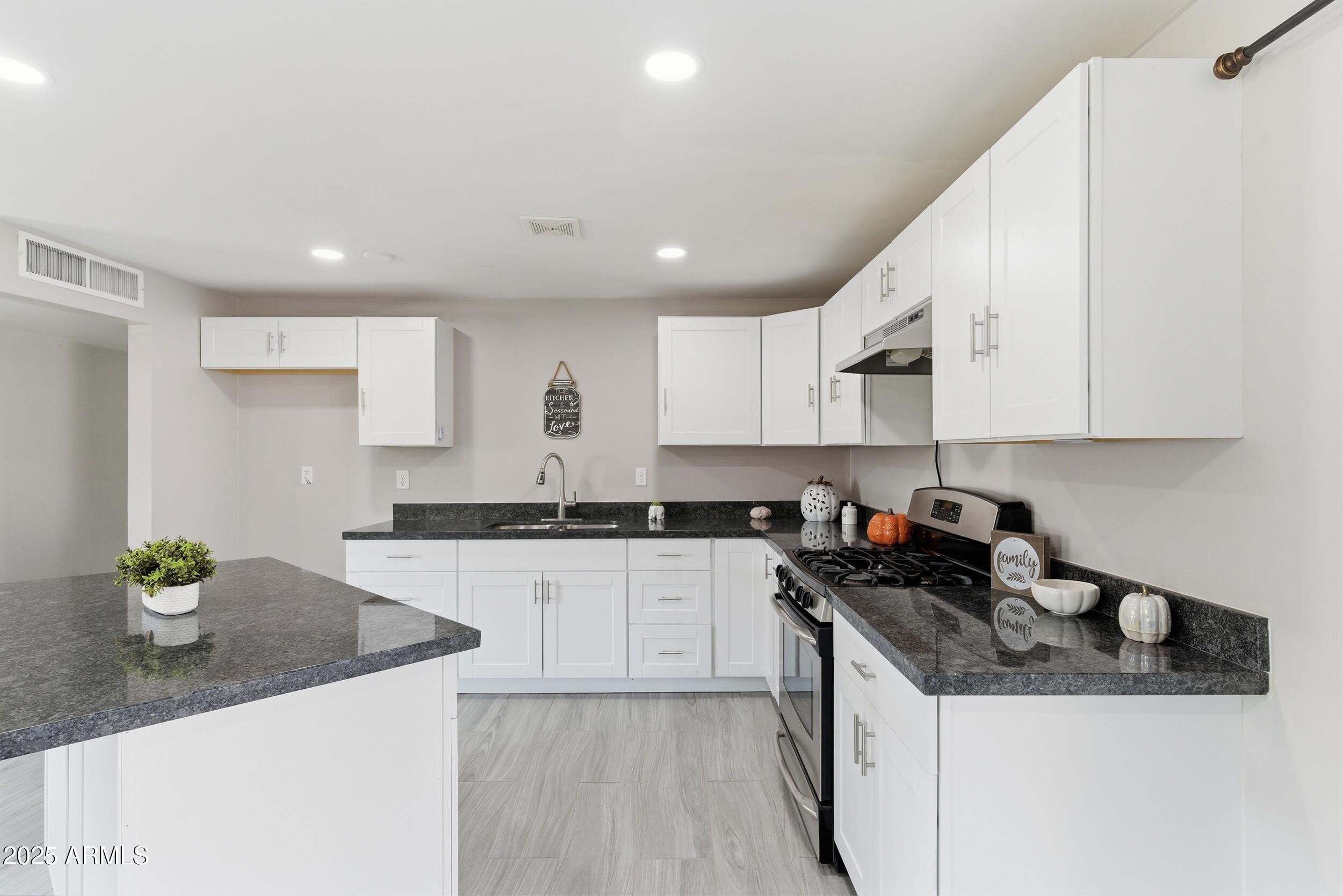 7150 West Montecito Avenue Phoenix, AZ 85033 - Photo 8 of 30 a kitchen with stainless steel appliances granite countertop sink stove top oven and cabinets