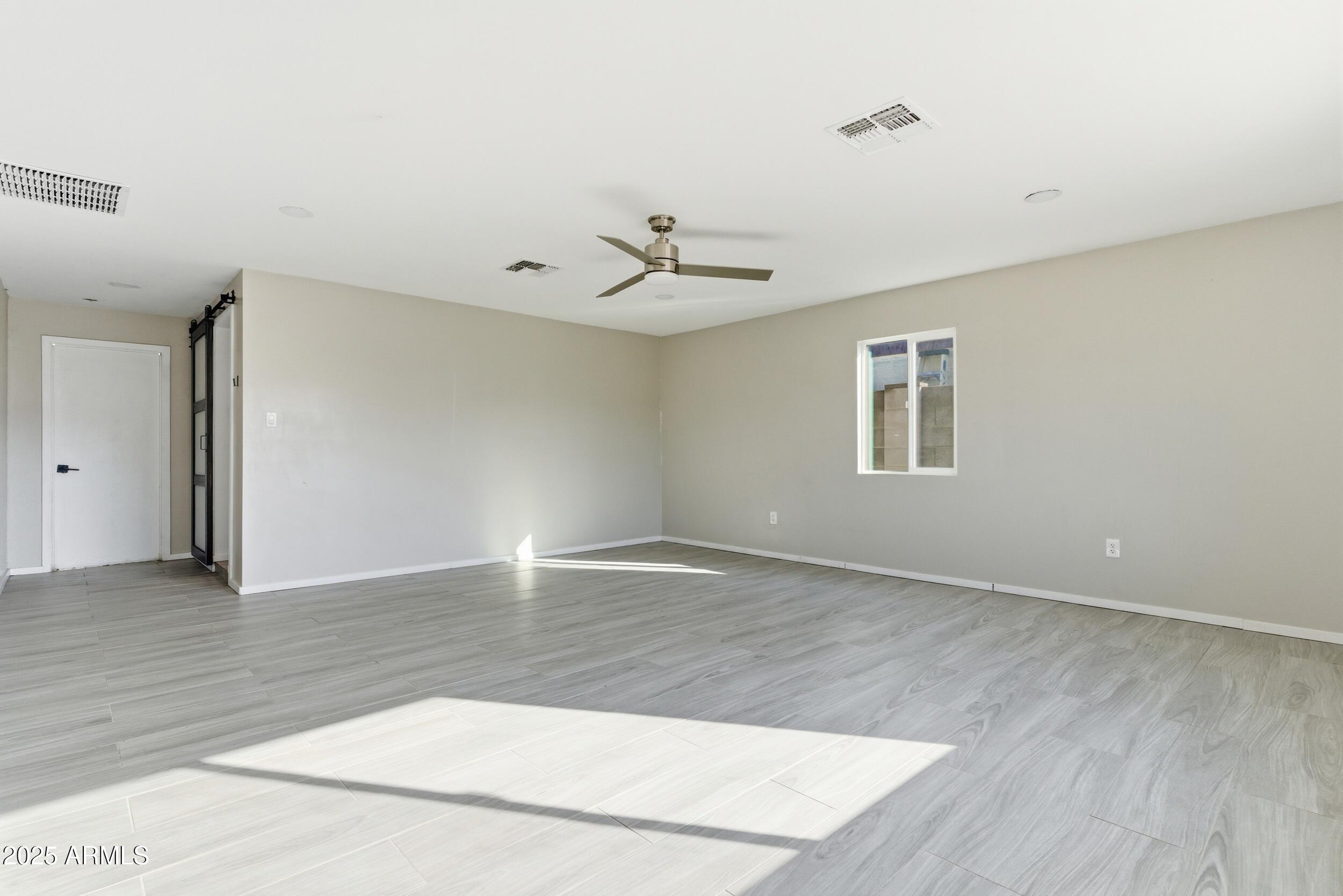 7150 West Montecito Avenue Phoenix, AZ 85033 - Photo 10 of 30 a view of an empty room with window and wooden floor