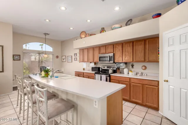 a kitchen with stainless steel appliances kitchen island granite countertop a stove a sink a refrigerator and white cabinets with wooden floor