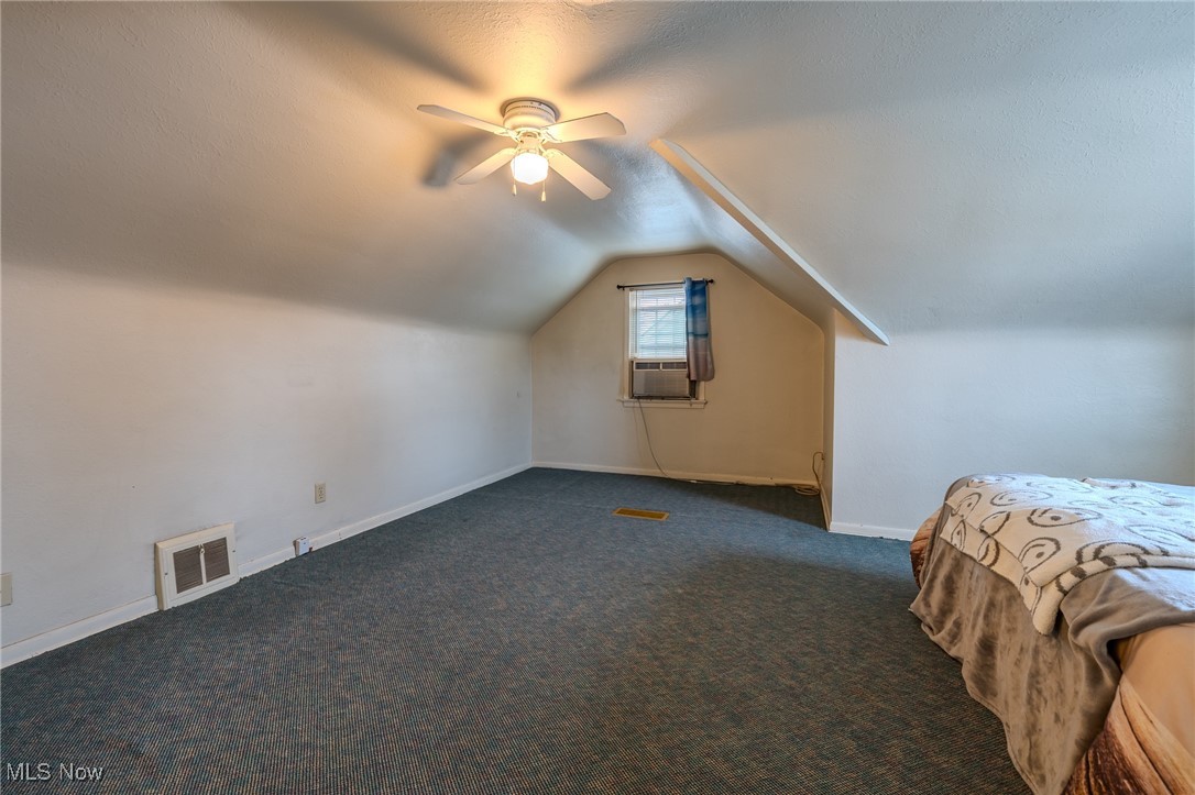 765 Pendley Road Willowick, OH 44095 - Photo 27 of 50 Unfurnished bedroom featuring cooling unit, ceiling fan, dark carpet, and vaulted ceiling