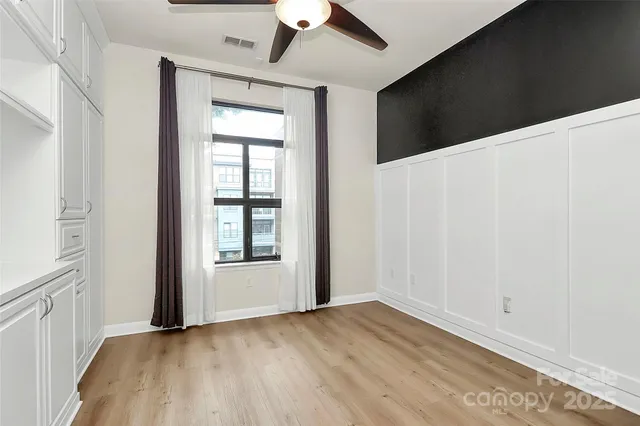 an empty room with wooden floor chandelier and windows