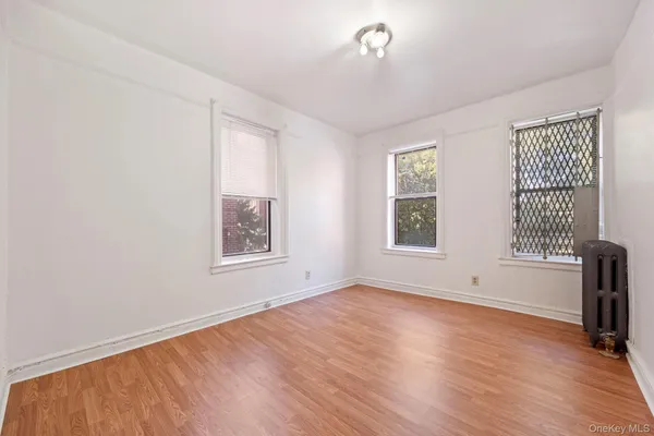 a view of an empty room with a window and wooden floor