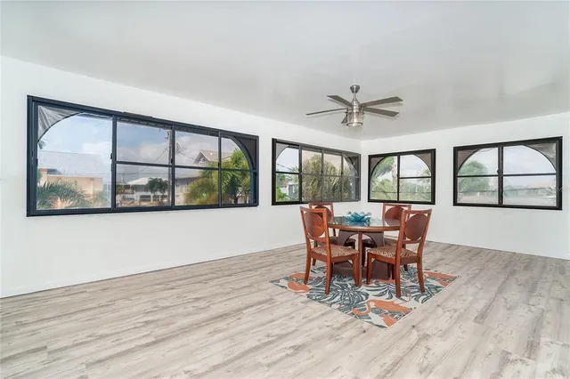 a dining room with wooden floor a chandelier a glass table and chairs
