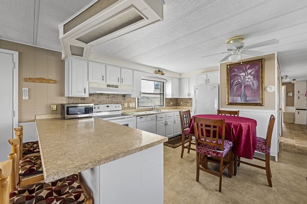 102 Peter Street Raynham, MA 02767 - Photo 7 of 23 a kitchen with stainless steel appliances granite countertop a table chairs sink and cabinets