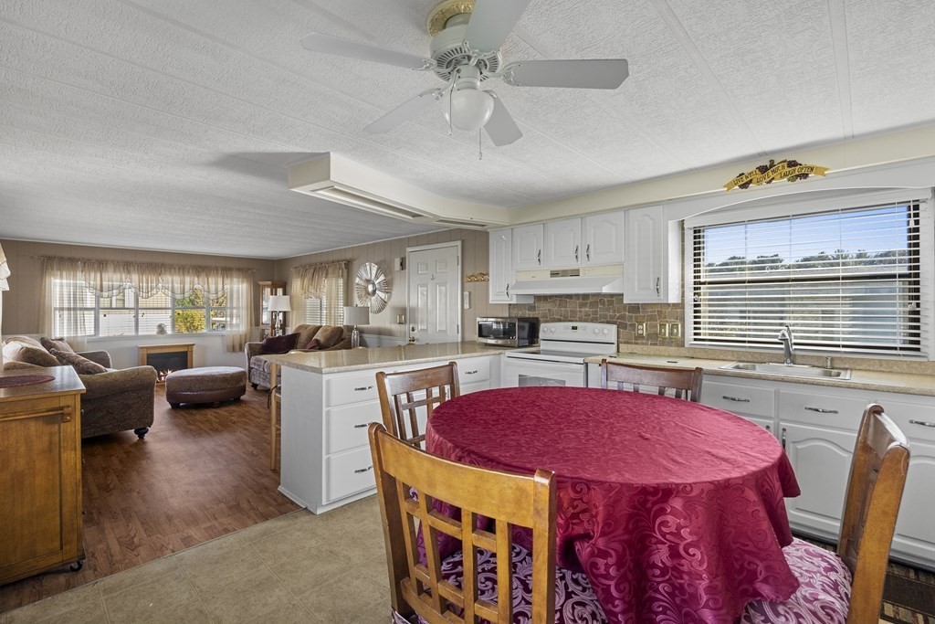 102 Peter Street Raynham, MA 02767 - Photo 8 of 23 a kitchen with kitchen island a stove a sink dishwasher a dining table and chairs with wooden floor