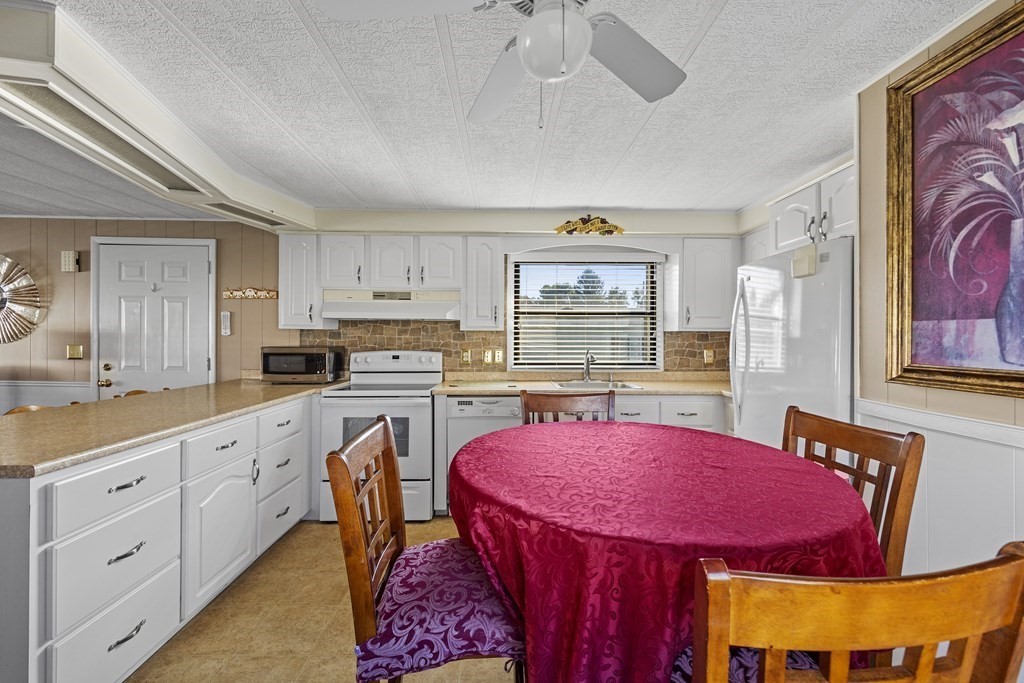 102 Peter Street Raynham, MA 02767 - Photo 9 of 23 a kitchen with stainless steel appliances kitchen island granite countertop a dining table chairs and white cabinets