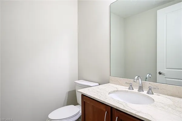 a bathroom with a granite countertop sink vanity mirror and toilet