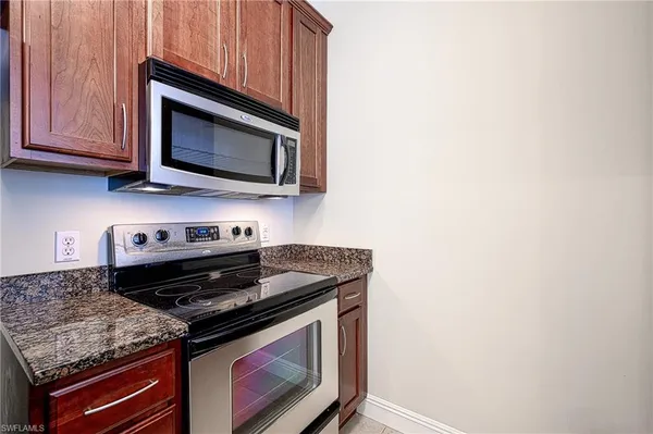 a kitchen with stainless steel appliances granite countertop white cabinets and a stove top oven