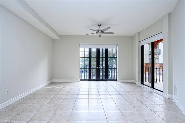 a view of an empty room with window and chandelier fan